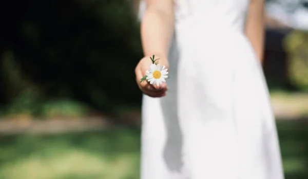 primer-plano-de-una-mujer-sosteniendo-una-flor-blanca-contra-un-fondo-borroso